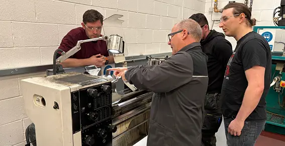 Colchester Training Academy teacher shows 3 Fibrelite employees how to use a lathe.